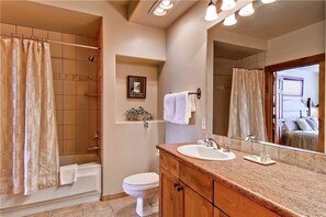 Une salle de bain équipée d’une douche, de toilettes, d’un lavabo et d’un grand miroir.