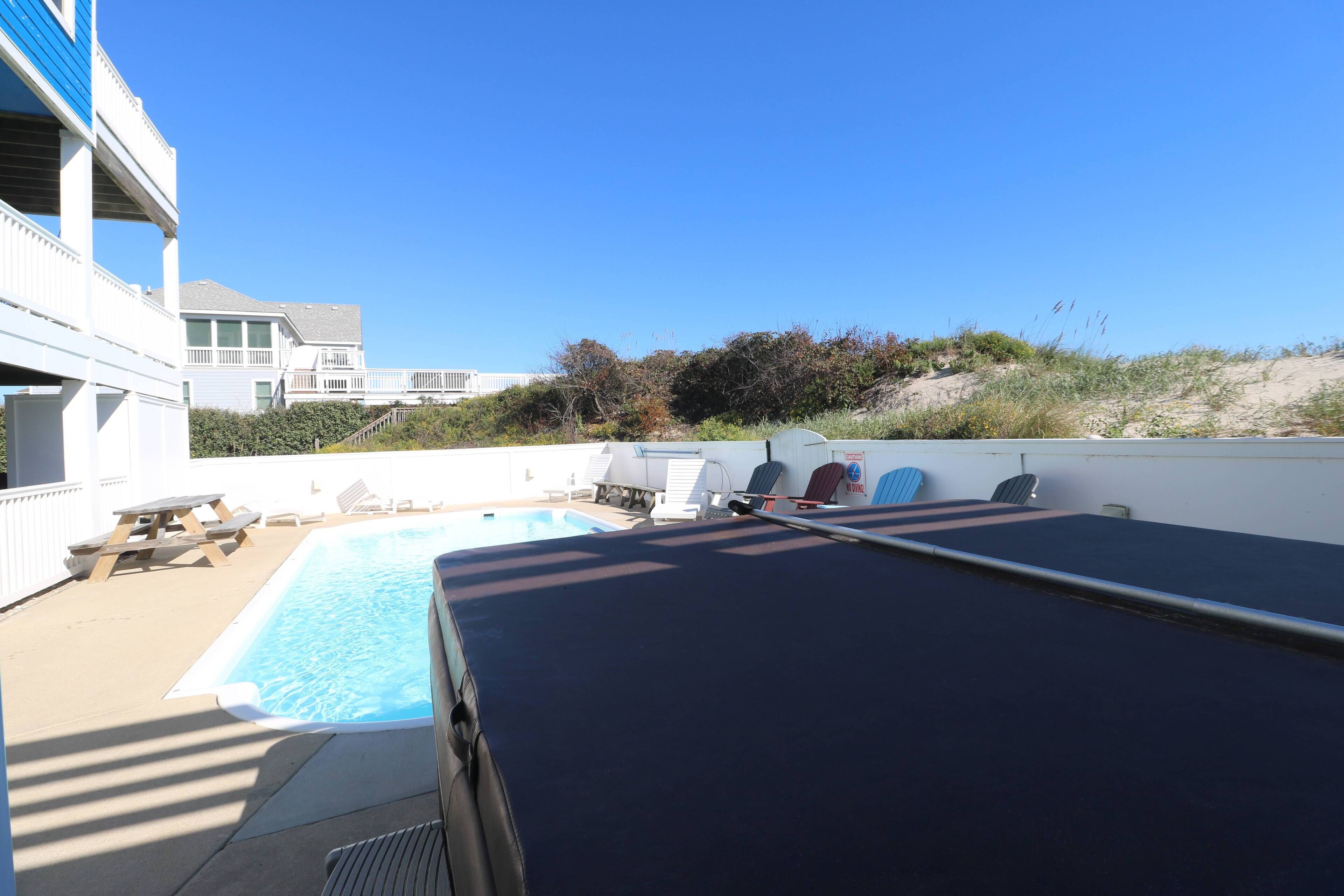 A rooftop pool area with lounge chairs and a view of the beach.