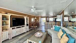 A spacious living room with a television, wooden entertainment unit, and a dining area with chairs and a table.