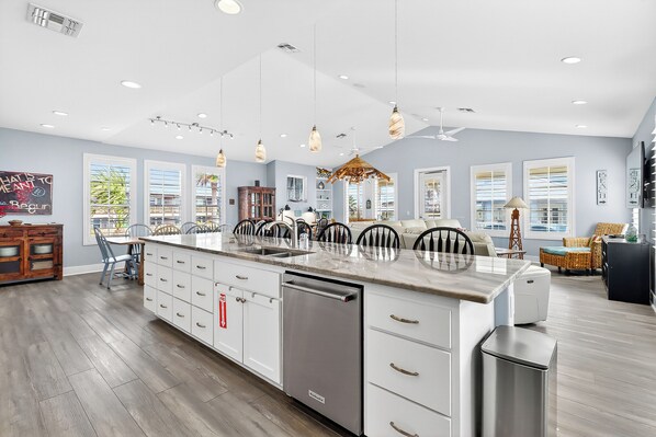 A modern kitchen with a central island, white cabinetry, and a built-in dishwasher.