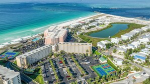 Vue aérienne d’un hôtel situé sur la côte, composé de plusieurs bâtiments, d’un parking et d’une zone de plage.
