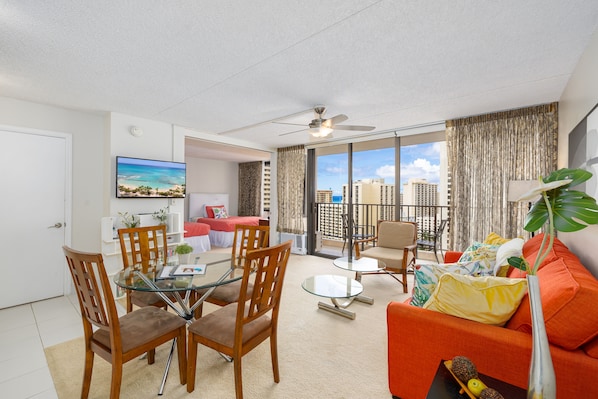 Relax in this stylish living room with a glass dining table, comfortable seating, and a balcony offering ocean views.