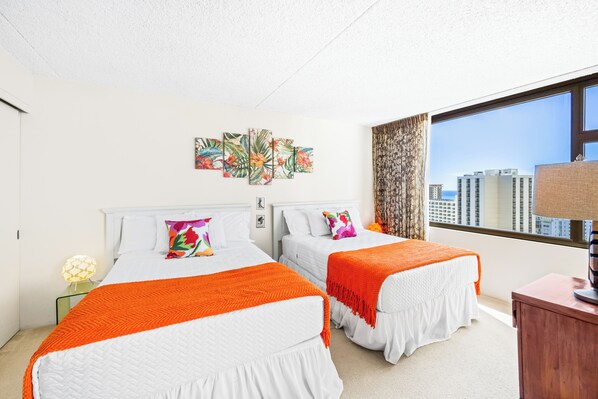 Quarto de hotel com duas camas, uma janela grande com vista para a cidade e uma obra de arte na parede.