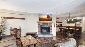 A spacious living room with a fireplace, leather sofas, a wooden coffee table, and a dining area with a wooden table and chairs.