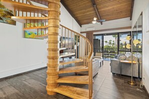 A wooden spiral staircase in a modern interior with a balcony and outdoor view. - Roomy Maui Suite w/Loft, Relaxing Lanai, Kitchen Ease, WiFi–Kamaole Sands 10408 (KIHEI)