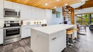 A modern kitchen with white cabinets, a marble island, stainless steel appliances, and a wooden ceiling. - Roomy Maui Suite w/Loft, Relaxing Lanai, Kitchen Ease, WiFi–Kamaole Sands 10408 (KIHEI)