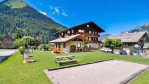 Un edificio de estilo chalet con techo inclinado, terraza de madera y una mesa de picnic al frente.