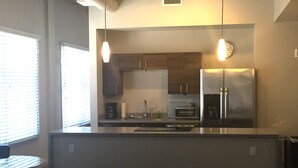 Una cocina moderna con una isla central, electrodomésticos de acero inoxidable e iluminación colgante.