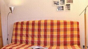 Una habitación acogedora con un sofá escocés, una mesita con una taza y un libro, y una pared decorada con marcos.