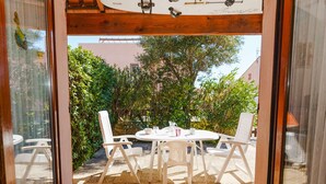 A patio with a round table and four chairs, surrounded by greenery and a building in the background. - 2-Room Pavilion + Mezzanine for 5, Terrace (Gruissan)