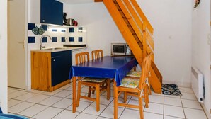 A compact kitchen with a dining area, wooden staircase, and basic amenities. - 2-Room Pavilion + Mezzanine for 5, Terrace (Gruissan)