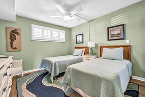 A bedroom with two beds, a ceiling fan, a window with blinds, and a seahorse artwork on the wall. - π΄ Welcome to Islander #105 β Your Fun & Relaxing Beach Escape! π
(Destin)