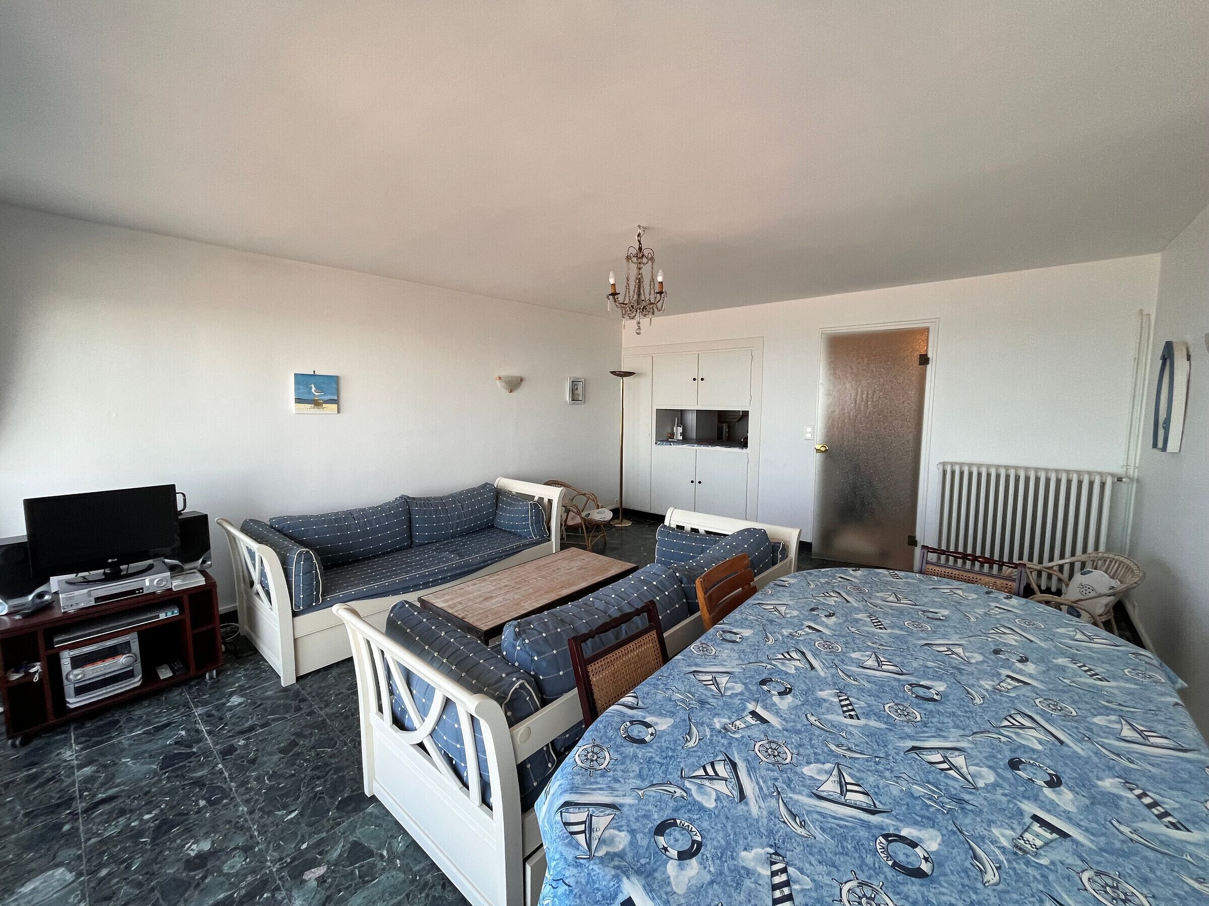 Et soveværelse med seng, sofa, fjernsyn, radiator og en dør.