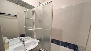 Un baño con lavamanos, espejo, ducha e inodoro.