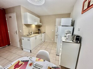 A compact kitchen with white cabinets, a sink, a stove, and a refrigerator.