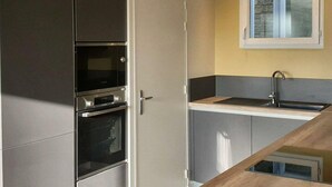Une cuisine compacte équipée d’un four encastré, d’un four à micro-ondes et d’un évier.
