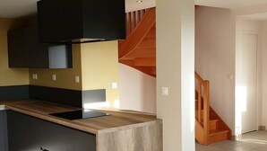 Une cuisine moderne avec des meubles de couleur sombre, un plan de travail en bois et une hotte noire.