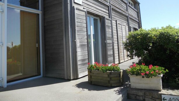 Un bâtiment moderne doté de grandes fenêtres et d’une porte, agrémenté de jardinières.