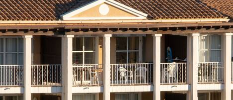 A building with a tiled roof, multiple balconies with white railings, and a central decorative element above the roofline.
