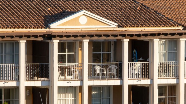 A building with a tiled roof, multiple balconies with white railings, and a central decorative element above the roofline.