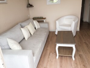 A living room with a grey sofa, white armchairs, and a wooden coffee table.