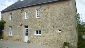 A stone building with a gabled roof, a central entrance, and multiple windows.