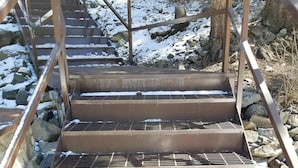A set of metal stairs with metal grates, surrounded by rocks and snow. - River Alpine Loft managed by Cabin Butler (Greer)