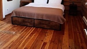 A bedroom with a wooden log wall, a bed with white bedding, and a wooden floor. - River Alpine Loft managed by Cabin Butler (Greer)