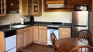 A kitchen with wooden cabinets, a stove, a sink, and a refrigerator. - River Alpine Loft managed by Cabin Butler (Greer)