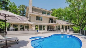 A two-story house with a swimming pool, outdoor furniture, and a covered patio area.