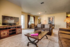 A living room with a flat-screen TV, a coffee table with a book, and two sofas.