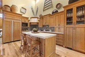 Une cuisine avec des meubles en bois, un îlot central doté de chaises, un four à micro-ondes et des objets décoratifs accrochés au mur.