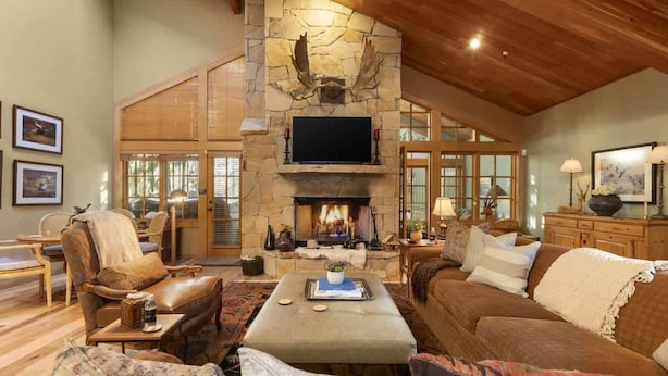 A spacious living room with a stone fireplace, wooden ceiling, and comfortable seating.