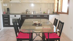 A dining area with a glass table and black chairs with red cushions. - RENTAL GITE BELOW VILLA (L'escarène)