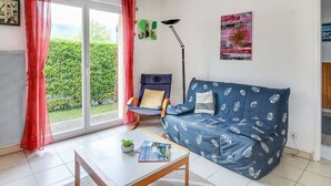 A living room with a sofa, a chair, a coffee table, and a floor lamp. - Calm T3 for 6, terrace, garden, near amenities (Esquièze-Sère)