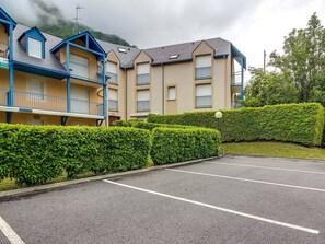 A multi-story hotel with balconies, a parking lot, and a well-maintained hedge. - Calm T3 for 6, terrace, garden, near amenities (Esquièze-Sère)