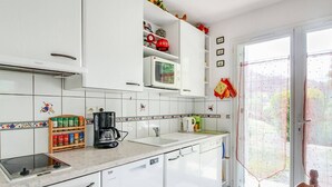 A modern kitchen with white cabinets, a built-in microwave, and a coffee maker on the countertop. - Calm T3 for 6, terrace, garden, near amenities (Esquièze-Sère)