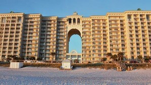 Un grand hôtel à étages multiples, doté de balcons et caractérisé par une entrée monumentale en forme d’arc.