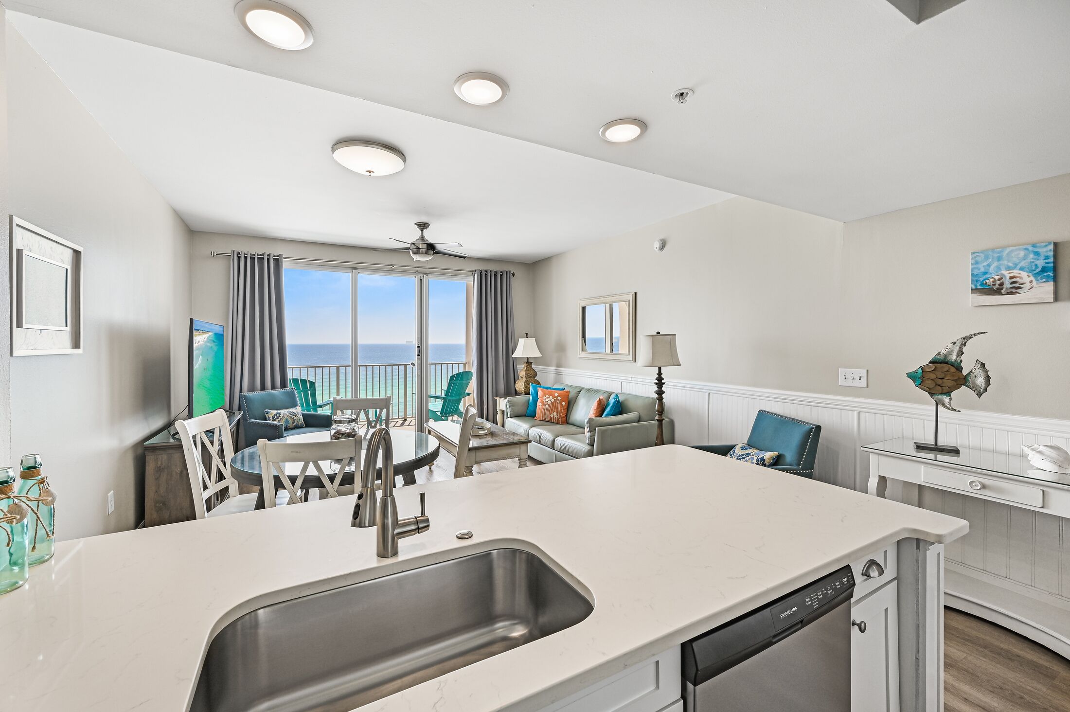 Een moderne keuken met een groot eiland, een eetgedeelte met stoelen en uitzicht naar buiten.