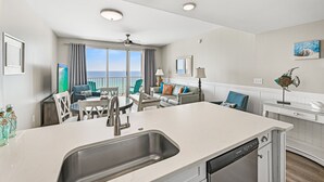 Une cuisine moderne dotée d’un grand îlot central, d’un coin repas avec des chaises et d’une vue sur l’extérieur.