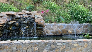 Ein Stehenfall und Teich in einem angelegten Garten.
