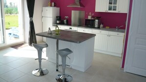 Une cuisine moderne avec des meubles blancs, un îlot central doté de tabourets, un four à micro-ondes et une cuisinière.