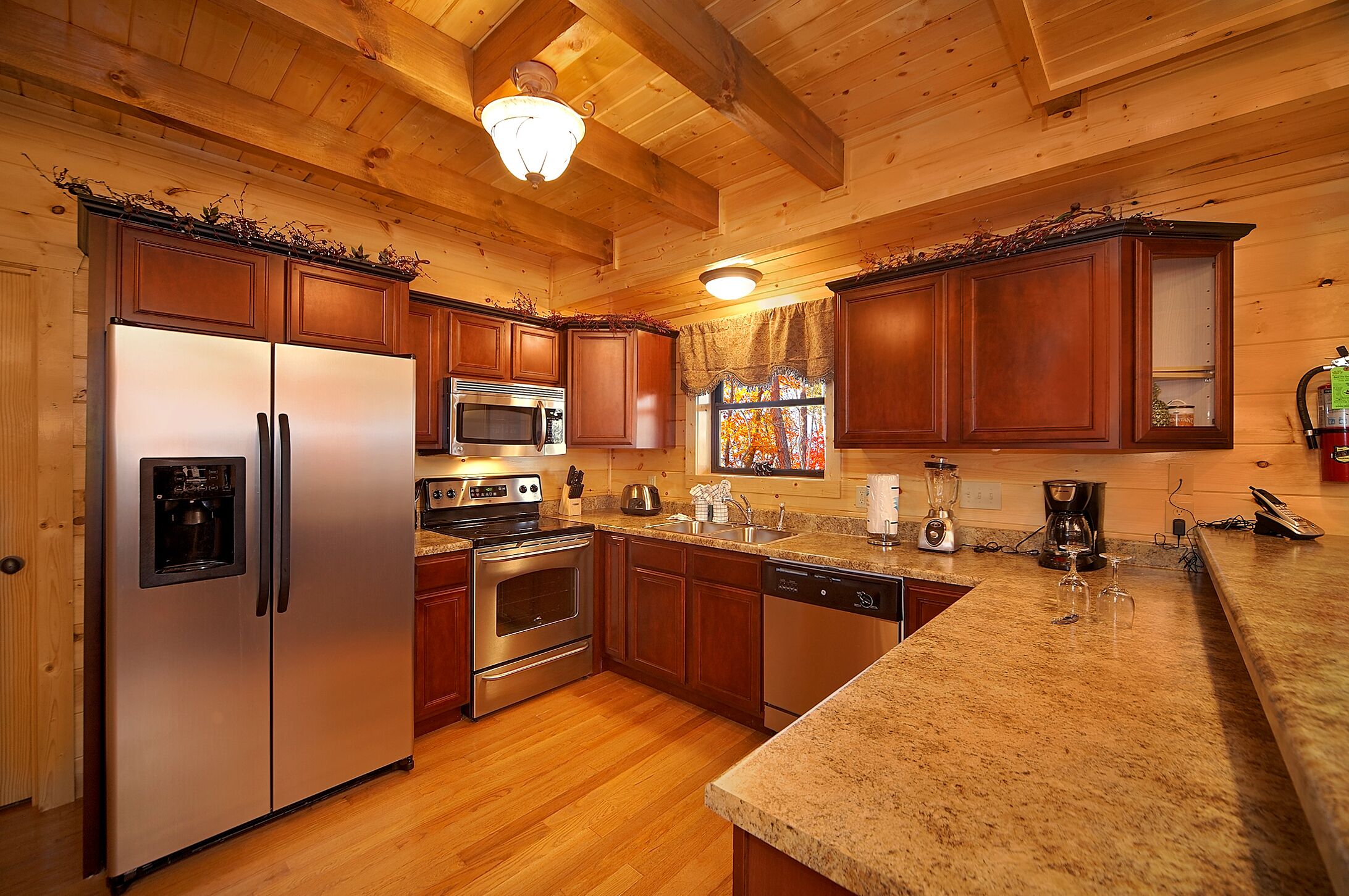 A kitchen with wooden cabinets, stainless steel appliances, granite countertops, and a wooden ceiling.