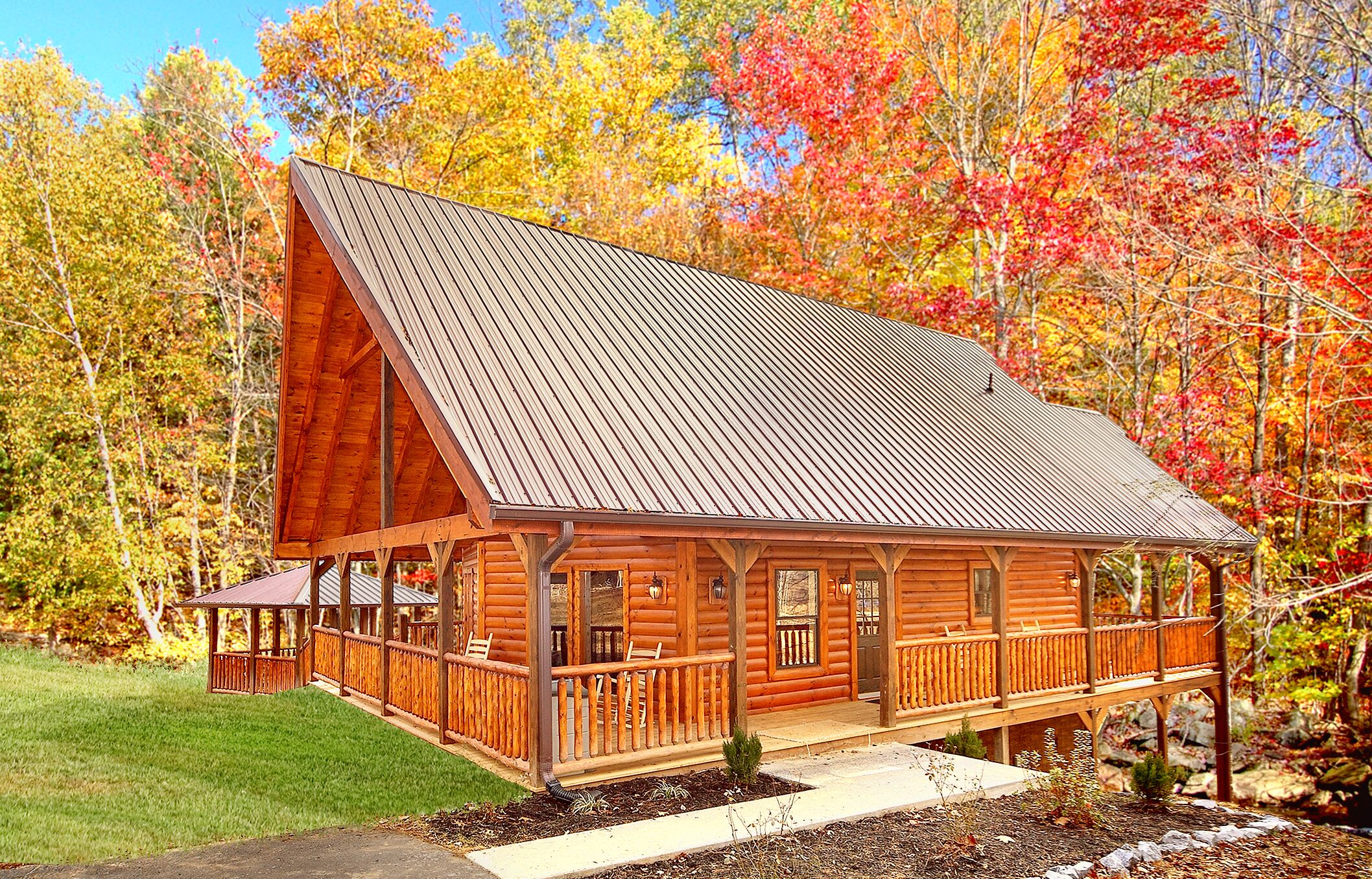 Une cabane en rondins dotée d’une grande véranda, d’une terrasse couverte et d’un toit en métal.