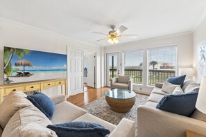 A living room with a sofa, armchair, coffee table, and a painting of a beach scene.