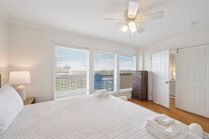 Un dormitorio con cama, ventilador de techo, cómoda y puerta que conduce a otra habitación.