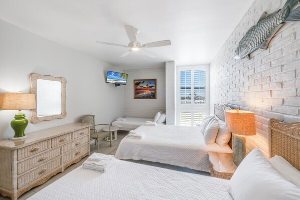Une chambre d’hôtel avec deux lits, une commode, un téléviseur et un mur décoré avec des motifs de poissons.