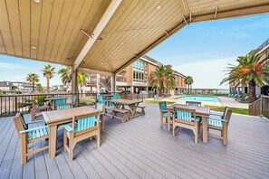 An outdoor deck with wooden furniture and a pool area. - This fabulous upscale condo, with elevator access, overlooks the ship channel an (Port Aransas)