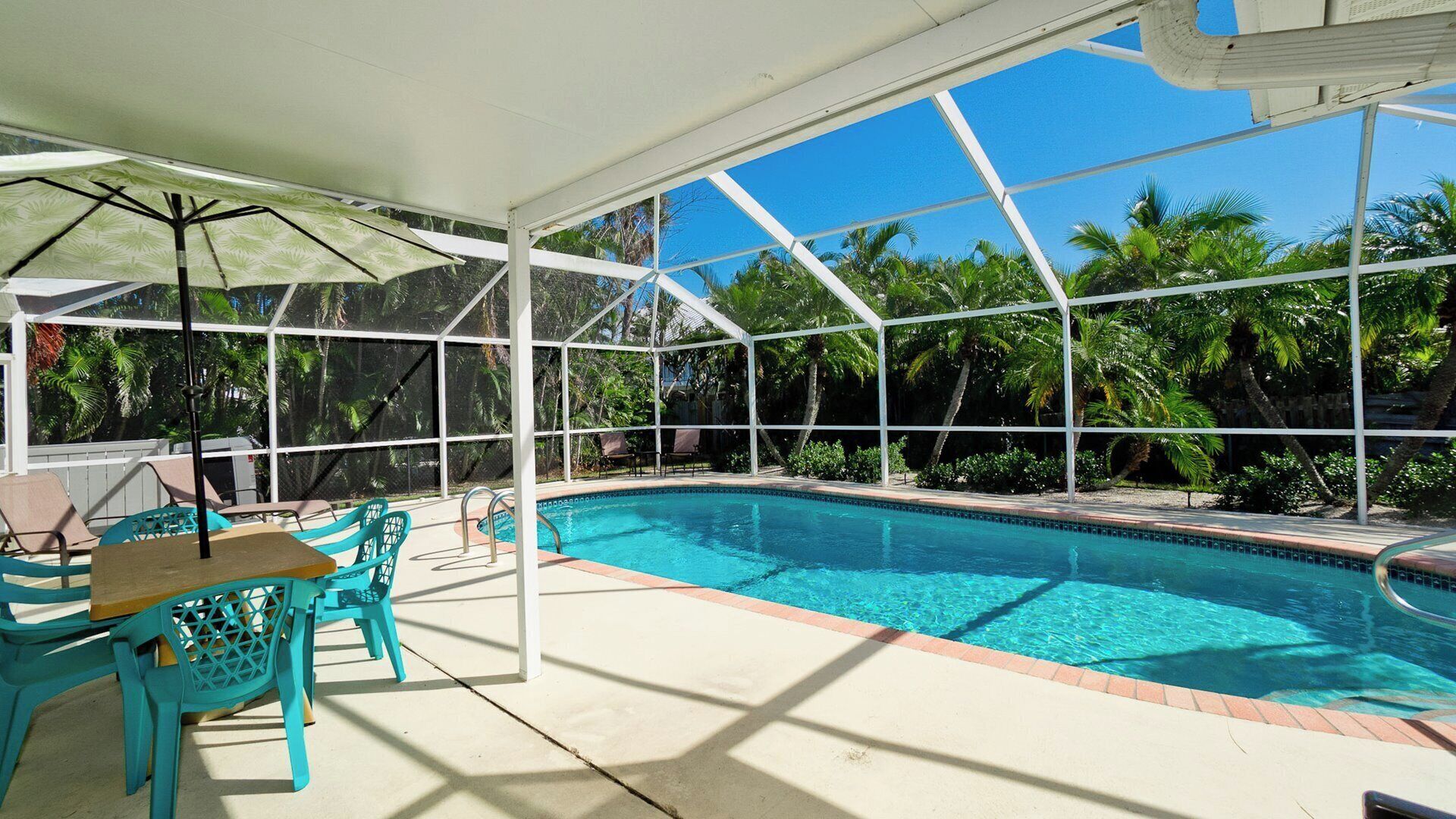 A covered swimming pool with a patio area, including chairs and a table.
