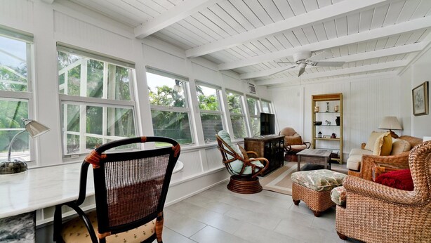 A sunlit room with large windows, wicker furniture, a ceiling fan, and a television. - 217 84th - Anna Maria Island- Private home 3 Bedroom/ 2 Bath with private pool , maximum occupancy of 6 people. (Holmes Beach)